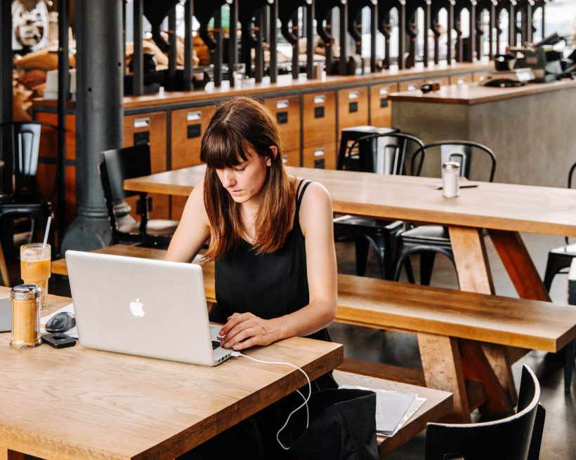 Image depicts a person in a restaurant working on their laptop