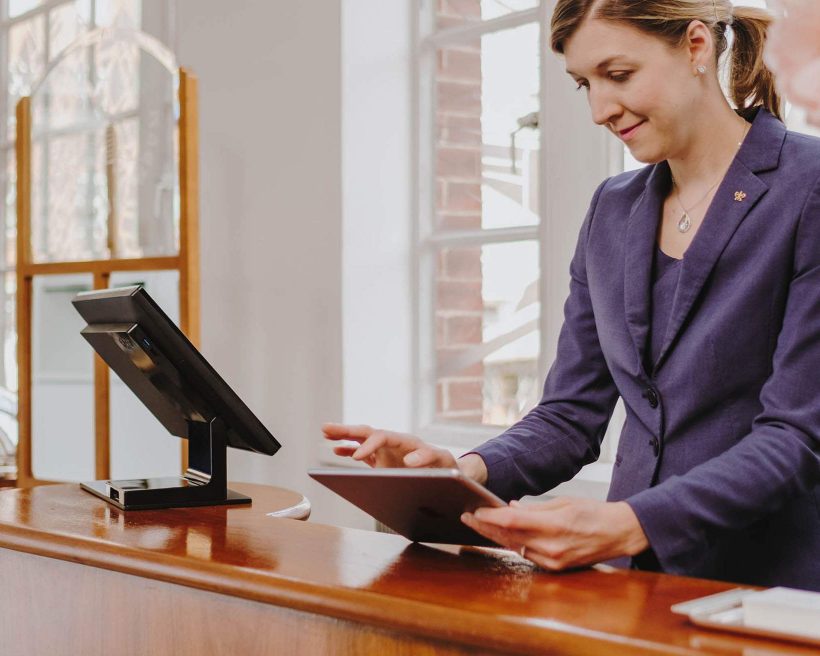 A woman is depicted while working at front desk stand, holding a table in her hands