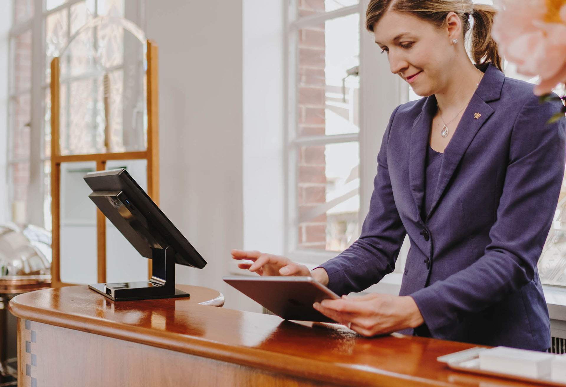 A woman is depicted while working at front desk stand, holding a table in her hands